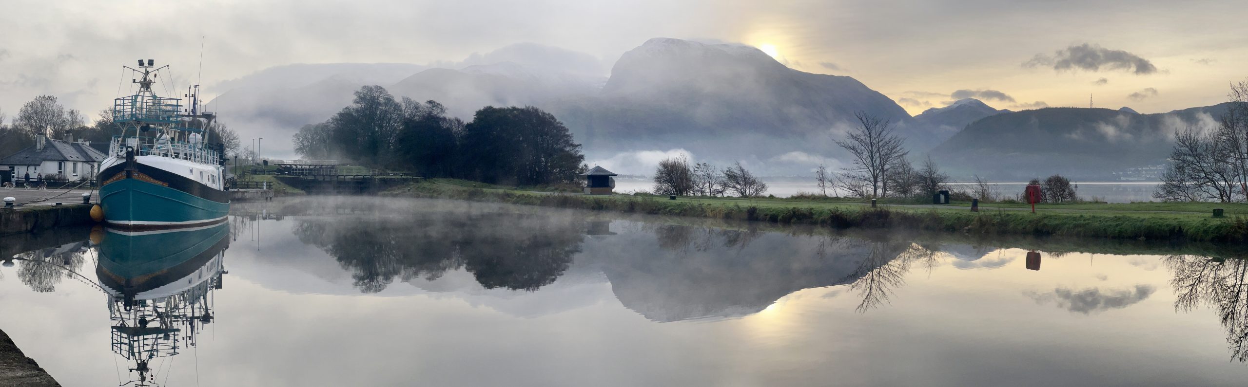 Ben Nevis from Corpach Basin on Loch Linnhe Mark Salisbury Scenic view of Ben Nevis from Corpach Basin on Loch Linnhe, featuring a moored fishing vessel, calm reflective water, misty mountains, and a soft sunrise sky in the Scottish Highlands.